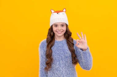 Mutlu genç kız sarı arka planda örülmüş şapka giyer, kışın.