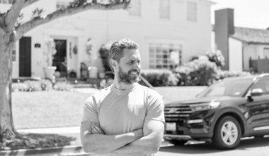 Gülümseyen kendine güvenen adam yeni ev ve arabada duruyor..