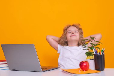 Dizüstü bilgisayar kullanan okul çocuğu. Okul ve çocuklar. Kitap okuyan sevimli sarışın çocuk. Bilgi günü