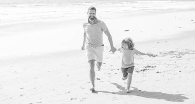 Baba ve çocuk yaz günü. Baba ve çocuk dışarıda eğleniyorlar. Çocukluk ve ebeveynlik. Neşeli baba ve oğul yaz plajında koşuyor. Aile seyahati ve tatil. babalar ya da aile günü