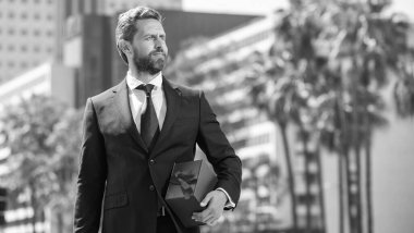 Takım elbiseli başarılı iş adamı hediye kutusunu dışarıda tutuyor..