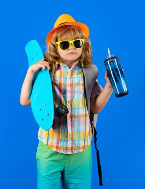 Çocukluk. Renkli arka planda kaykay ve su şişesi olan tatlı bir çocuk. Komik çocuk, stüdyoda kaykay tutan şık bir kaykaycı.