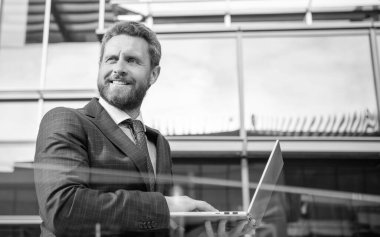 Neşeli profesyonel ağ yöneticisi bilgisayarı elinde tutuyor. Modern kablosuz bilgisayarı olan patron. İş adamı çevrimiçi çalışıyor. İş başarısı. Programcı bilgisayar kullansın. Girişimci. çevik iş.