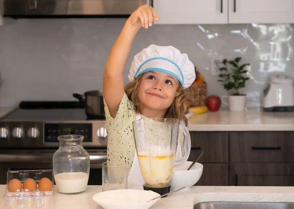 Kid chef cook in chef hat preparing food on kitchen. Child making tasty delicious. Cooking meal