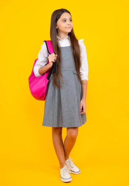 Back to school. Teenager school girl in school uniform with bagpack. School children on isolated studio background