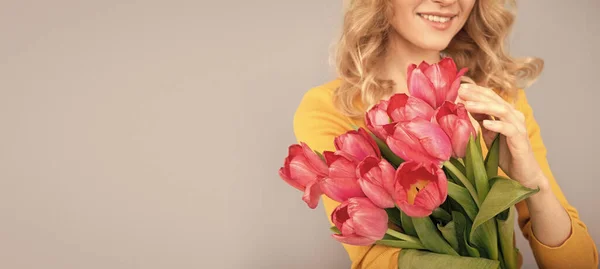 cropped smiling woman with tulips. lady hold flowers for spring holiday. girl with bouquet on grey background. floral present for womens day. 8 march and mothers day. copy space.