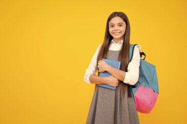 Okula dönelim. Ergen liseli kız kitaplarını ve kitaplarını öğrenmeye hazır tutuyor. İzole edilmiş sarı stüdyo geçmişi olan okul çocukları.