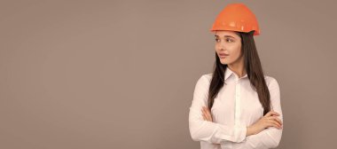 confident lady in safety hardhat and white shirt crossed hands looking aside, copy space, confidence. Woman isolated face portrait, banner with mock up copy space