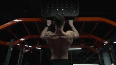 Kaslı sporcu spor salonunda, arka planda. Spor salonunda barfiks çeken sporcu. Sporcu spor salonunda spor malzemeleri ile barfiks çekiyor..