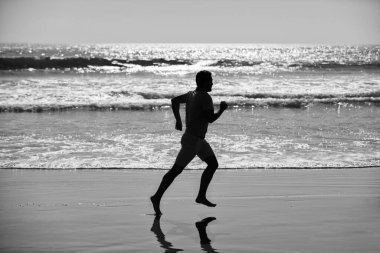 silhouette of sporty man runner sprinting on beach outdoor, achievement.