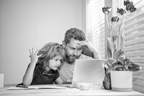 bearded dad or school private tutor teaching boy son with modern laptop, video conference.