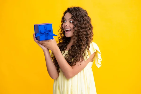 Child with gift present box on isolated background. Presents for birthday, Valentines day, New Year or Christmas. Excited teenager, glad amazed and overjoyed emotions