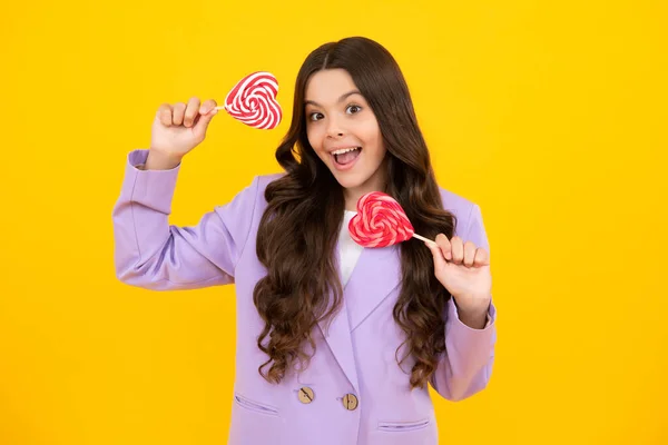 Teenage girl with candy lollipop, happy child 12, 13, 14 years old eating big sugar lollipop, sweets candy. Happy teenager, positive and smiling emotions of teen girl