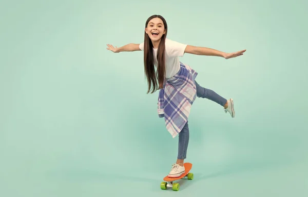Teen hipster girl skater with skateboard on isolated background. Summer kids trend, urban teenage style. Jump and run. Happy teenager, positive and smiling emotions of teen girl
