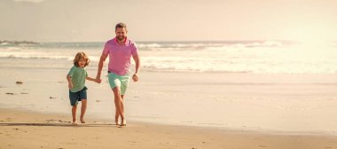 Baba ve oğulun bayrağı yaz deniz sahillerinde koşuyor. Mutlu baba ve oğul yaz plajında koşuyor..