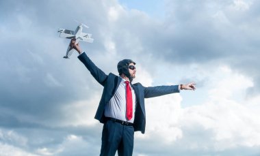 ambitious businessman in suit and pilot hat launch plane toy on sky background.