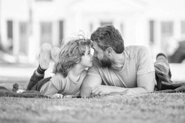 Ebeveynlik ve babalık. Babalar günü. Mutlu baba ve oğul parkta eğleniyor. Güzel bir aile değeri. Çocukluk ve ebeveynlik. Ebeveyn, küçük çocuk çimlerin üstündeyken rahatlar. Baba ve çocuk yaz günü.