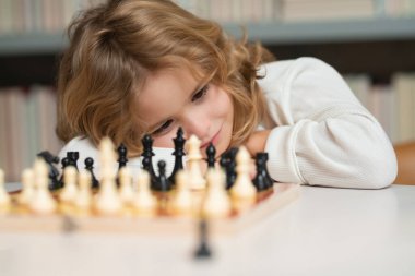 Smart kid playing chess. Clever child thinking about chess. Kids early development. Boy kid playing chess at home. Portrait close up