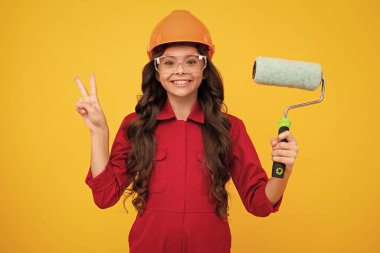 Renovation for childrens room. Little girl in protective helmet and paint brush for painting walls. Happy face, positive and smiling emotions of teenager girl