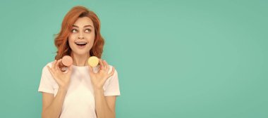 amazed girl hold sweet macaron french cookie on blue background. Woman isolated face portrait, banner with mock up copyspace