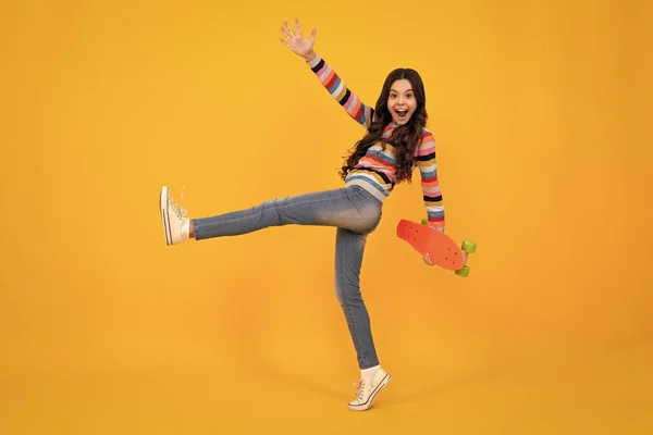 Jump and run. Amazed teenager. Teen school girl with skateboard on studio isolated background. Spring schoolgirl trend, urban teenager style. Excited teen girl