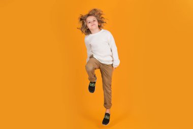 Funny boy jumping in air. Full body of little child jump wear casual t-shirt and jeans isolated on yellow background