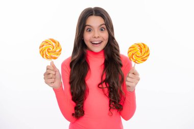 Şekerli lolipop yiyen genç bir kız. Çocuklar için şeker ve şeker. Çocuk beyaz izole arka planda lolipop yiyor. Lezzetli karamel, şekerci dükkanı. Mutlu kız yüzü