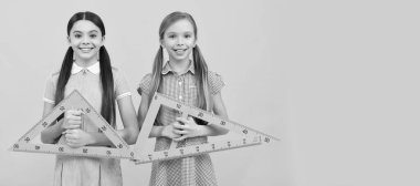 School girls friends. Happy kids hold triangular rulers. Geometry lesson. School education. Banner of schoolgirl student. School child pupil portrait with copy space