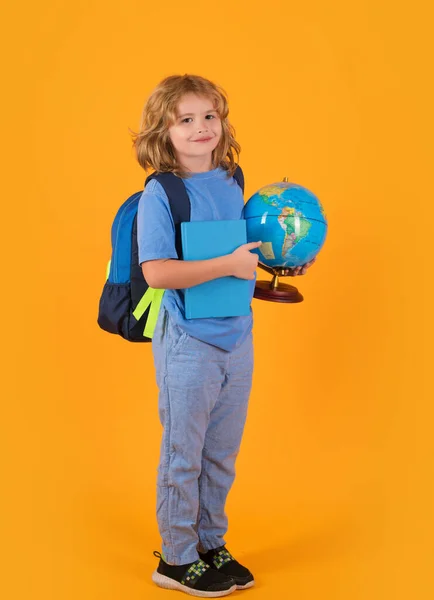 School boy with backpack globe and book. Little student on yellow isolated background. Learning, education and knowledge