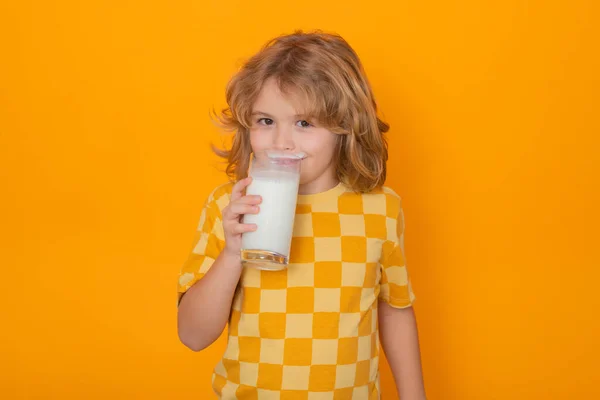 Cute child drinking milk on yellow background