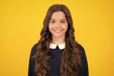 Portrait of cute positive little girl isolated on yellow background. Attractive caucasian child smiling and looking at camera