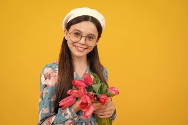 Stüdyonun sarı arka planında bir buket lale olan genç kız. Çiçekleri seven kız