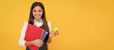 Elma ve kitaplarla okula dönen mutlu çocuk sarı arka plan, eğitim. Liseli kız öğrencinin yatay izole edilmiş posteri. Liseli kızların afiş başlığı fotokopi alanı