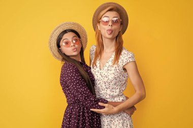 Sarı arka planda hasır şapkalı anne ve kız.