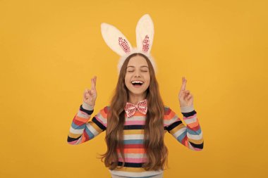 Tavşan kulaklı mutlu Paskalya çocuğu ve sarı arka planda papyon. Bir dilek tut..