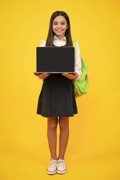 Teen schoolgirl hold laptop on isolated studio background. Cchool student learning online, webinar, video lesson, distance education. Screen of laptop computer with copy space mockup