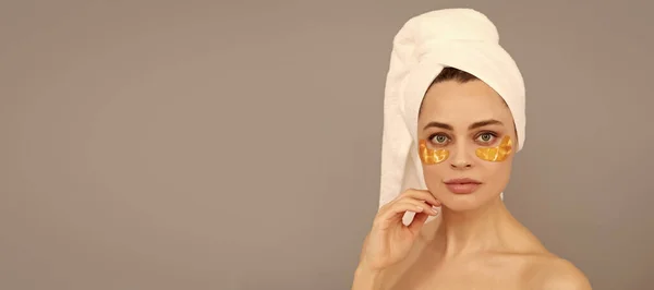 Eye patches, patch under eyes. sensual lady with terry towel use facial golden eye patch for skin, hydrogel. Beautiful woman isolated face portrait, banner with mock up copy space
