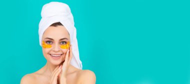 Eye patches, patch under eyes. happy young lady has collagen golden eye patches on face with towel. Beautiful woman isolated face portrait, banner with mock up copy space