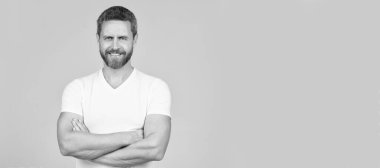 Happy confident man smile keeping arms crossed in white tshirt grey background, guy. Man face portrait, banner with copy space