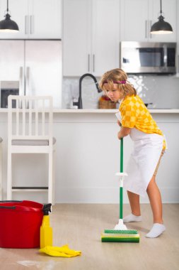 Child do chores cleaning floor. Little kid cleaning at home. Child doing housework having fun. Portrait of child housekeeper with wet flat mop on kitchen interior background