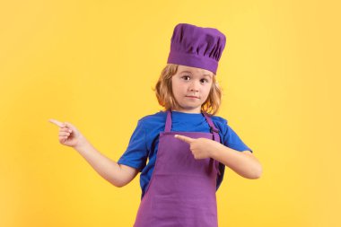 Cooking, culinary and kids. Little boy in chefs hat and apron on studio isolated background