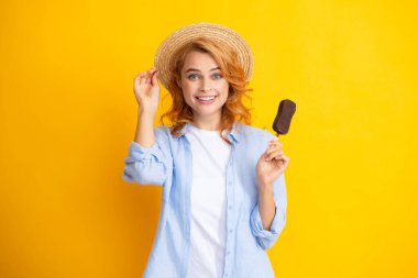 Moda portresi, sarı arka planda dondurması olan havalı genç bir kadın. Genç küstah hippi kız sopa için dondurma yiyor.