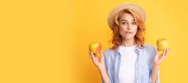 Summer female model with apple. cheerful young woman in summer straw hat with apple licking lips, yummy. Woman isolated face portrait, banner with mock up copy space