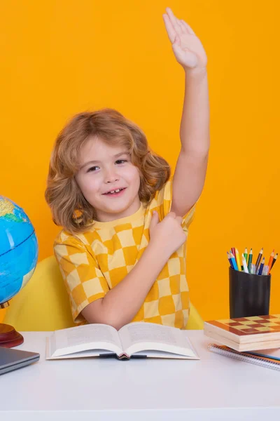 School child raising hands, willing to answer question. School child student learning in class, study english language at school. Elementary school child. Portrait of funny pupil learning