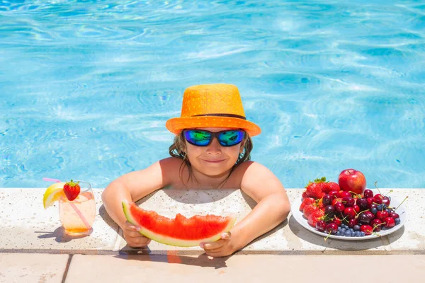 Child in swimming pool playing in summer water. Vacation and traveling with kids. Summer fruits for children