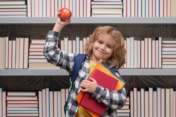 School boy with books and apple in library. Nerd school kid. Clever child from elementary school with book. Smart genius intelligence kid ready to learn. Hard study