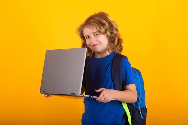 School child using laptop computer. Nerd school kid isolated on studio background. Clever child from elementary school with book. Smart genius intelligence kid ready to learn. Hard study