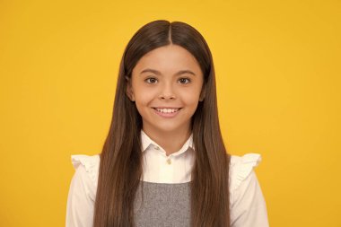 Mutlu kız yüzü, pozitif ve gülümseyen duygular. Kafkasyalı genç kızın yakın portresi. Sarı izole edilmiş stüdyo arka planında sevimli bir gencin fotoğrafı.