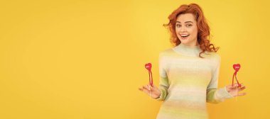 İzole edilmiş yüz portresi, fotokopi alanı olan pankart. Kırmızı kalpli mutlu kızıl kız sarı arka plana yapışıyor.