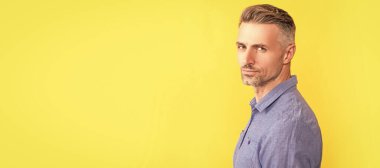 İnsan yüzü portresi, fotokopi alanı olan pankart. Gri sakallı ciddi bir adam. Saç ve sakal bakımı. Sarı arka planda erkek manken